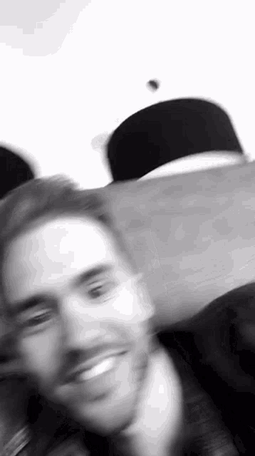 a blurry black and white photo of a man smiling .