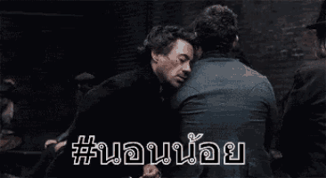 two men are standing next to each other in a dark room talking to each other .