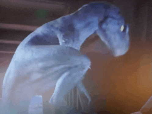 a blue monster is standing in a dark room with a blurred background