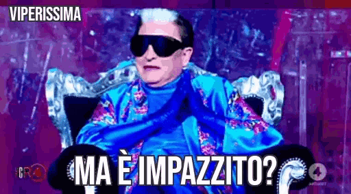 a man wearing sunglasses and a blue shirt is sitting in a chair with the words ma e impazzito written below him