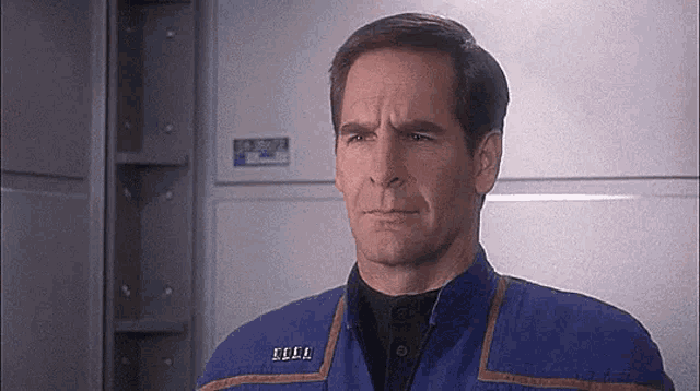 a man in a blue jacket with a name tag on his chest is making a funny face .