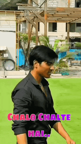 a man in a black shirt is standing on a green field and says chalo chalte hai