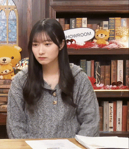 a woman sitting at a table with a sign that says howroom