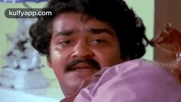 a man with a mustache and curly hair is looking at the camera .