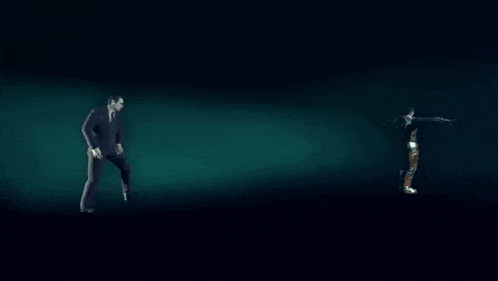 two people are standing in the dark and one is pointing at the other