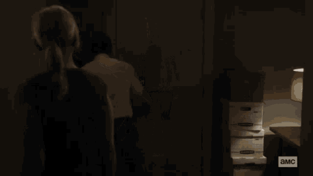 a man in a white shirt is standing in a dark room with a sign that says ' a.m.c. '
