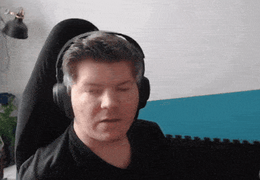 a man wearing headphones looks at the camera with his eyes closed