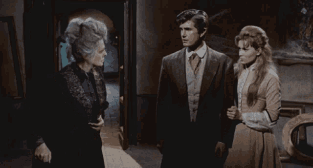 a man and two women are standing in a dark hallway
