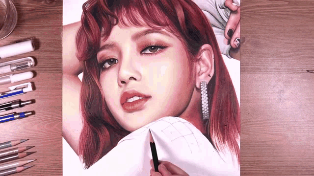 a drawing of a woman with red hair and earrings is on a table