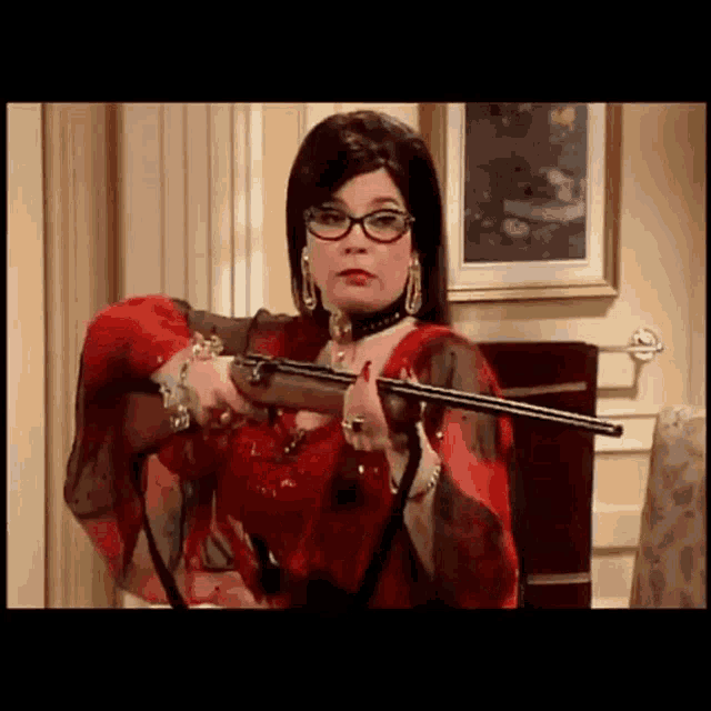 a woman in a red dress is holding a rifle