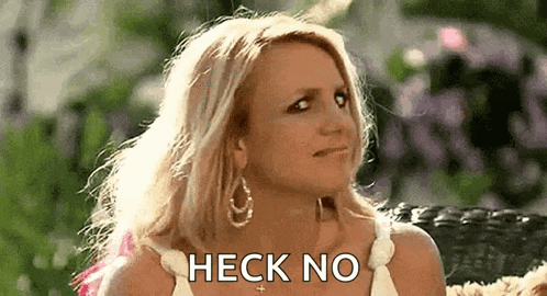 britney spears is sitting on a couch with her hair blowing in the wind and making a funny face .