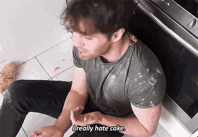 a man is sitting on the floor with a dirty shirt and says " i really hate cake "