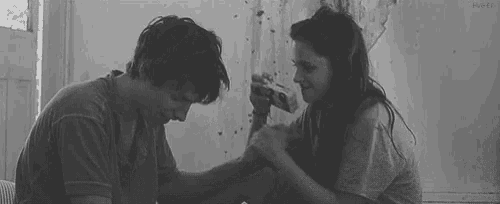 a man and a woman are sitting next to each other and holding hands .