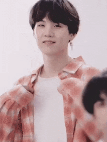 a close up of a person wearing a pink plaid shirt and a white shirt .