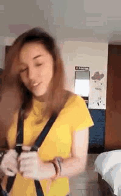 a woman in a yellow shirt is holding a cell phone in her hand .
