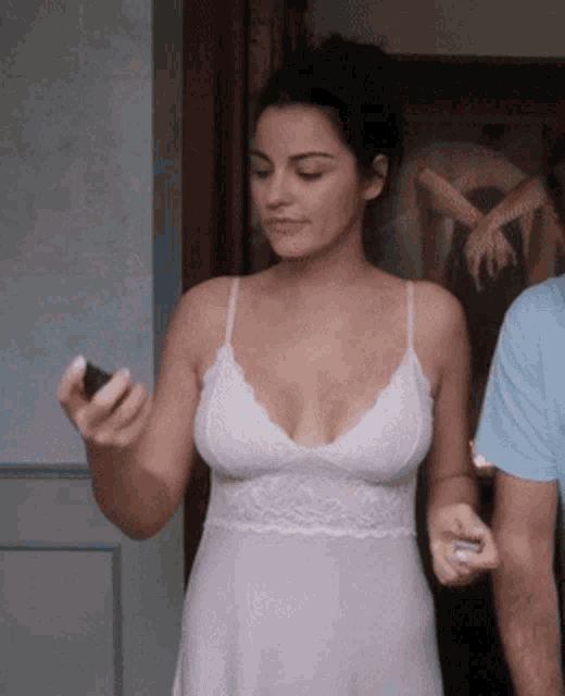 a woman in a white lace dress holds a cell phone in her hand
