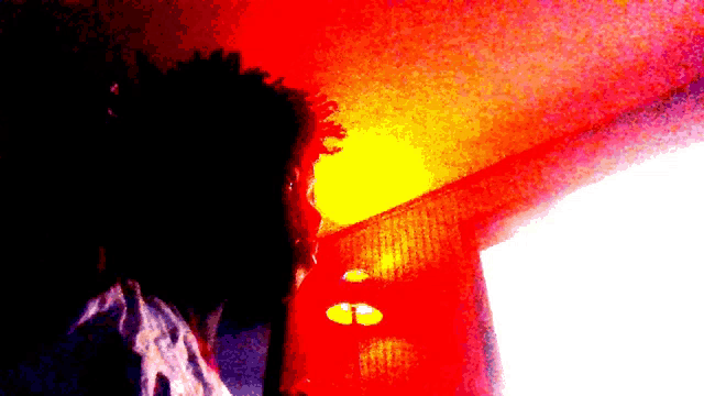a clown is standing in front of a window with a red light behind him