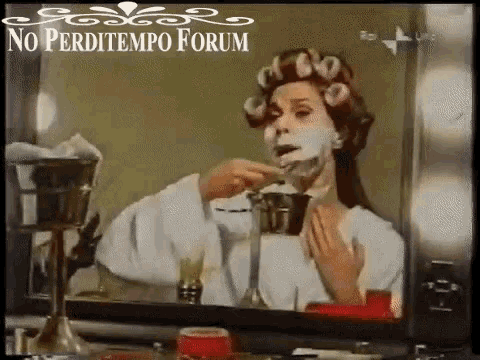 a woman with curlers on her head is applying a mask to her face in front of a mirror .