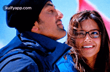 a man and a woman are smiling and looking at each other . the woman is wearing glasses .