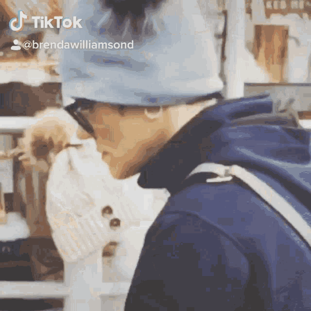 a man wearing a blue beanie and a blue hoodie has a tiktok sticker on his face