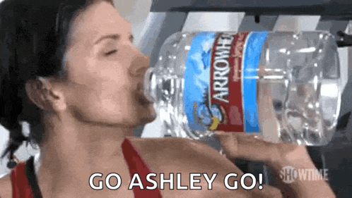 a woman is drinking water from a bottle that says arrowhead