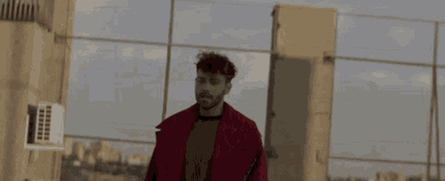 a man in a red coat is standing in front of a fence