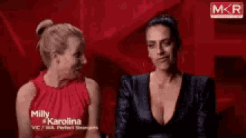 two women are sitting next to each other on a red background and one of them is named milly karolina