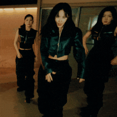 a woman in a black jacket and black pants is dancing with two other women
