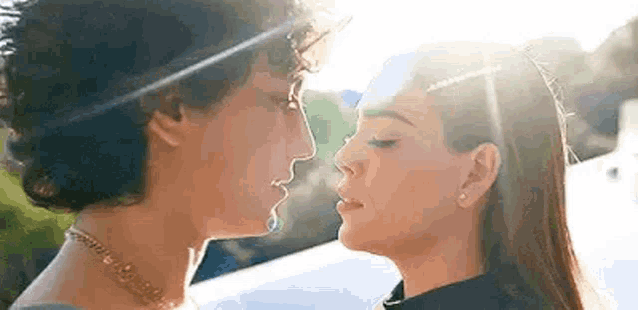 a man and a woman are kissing each other in front of a car .