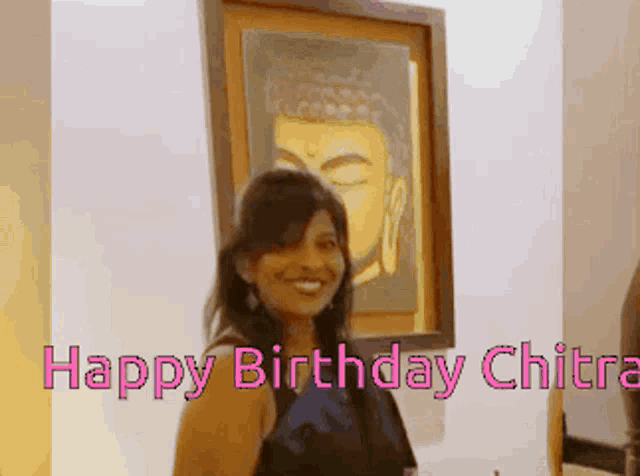 a woman stands in front of a buddha painting with the words happy birthday chitra below her