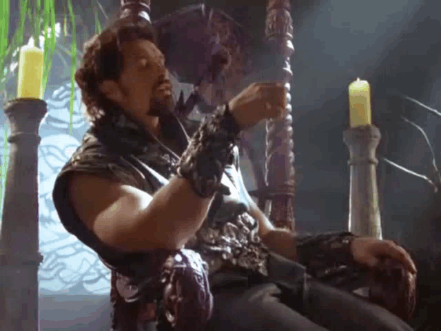 a man with a beard is sitting on a throne with candles in the background