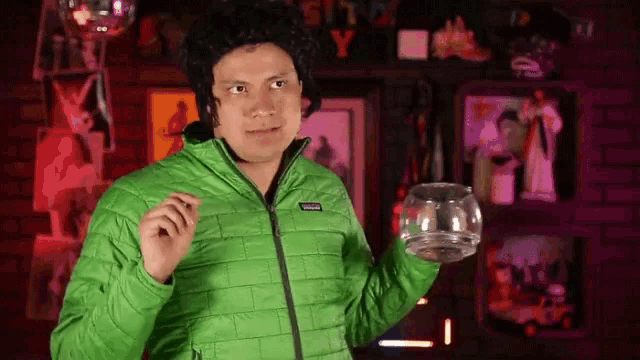 a man in a green patagonia jacket holds a glass bowl in his hand
