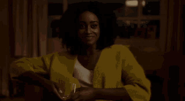 a woman in a yellow sweater is holding a glass of wine