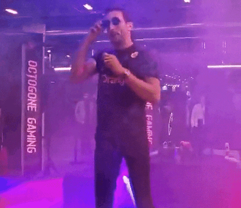a man is singing into a microphone in front of a sign that says octogone gaming .