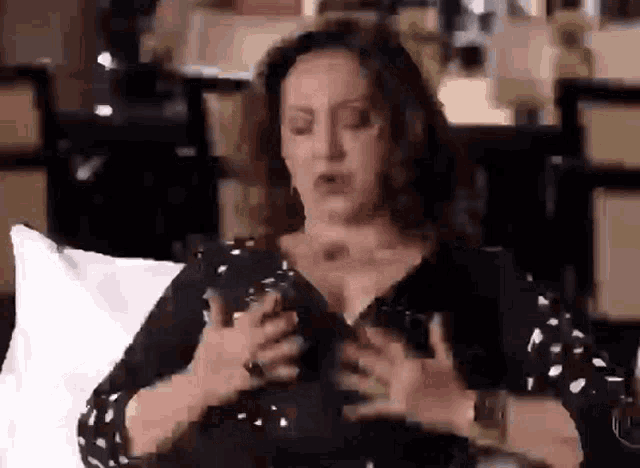a woman is sitting on a couch with her hands on her chest .