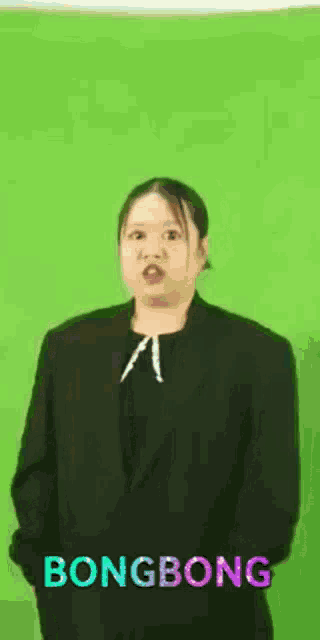a woman in a suit is standing in front of a green screen with the words bongbong written on it .