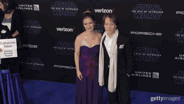 a woman in a purple dress stands next to a man on a star wars event