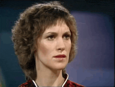 a close up of a woman 's face with curly hair and a serious look on her face .