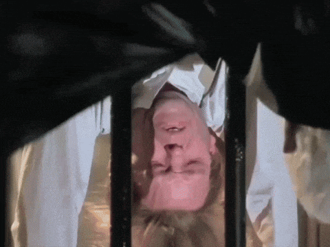 a man is laying upside down in a cage with his eyes closed