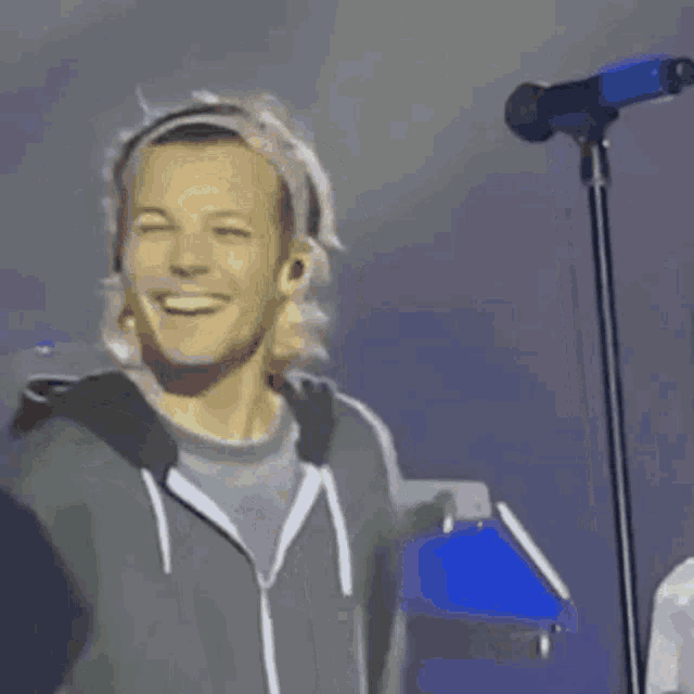 a man is smiling while standing in front of a microphone on a stage