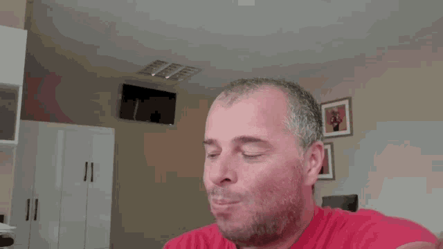 a man in a red shirt is making a funny face in a living room