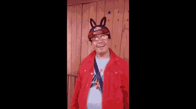 a man wearing a red jacket and a hat with bunny ears .