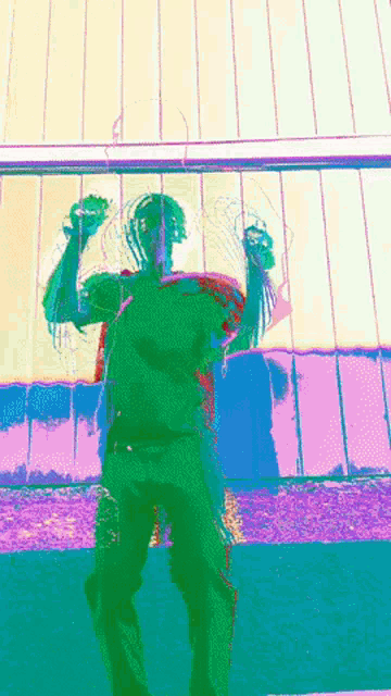 a man in a green shirt is standing in front of a fence