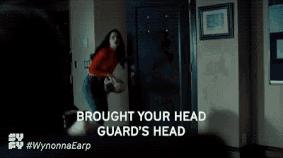 a woman in a red shirt is standing in a dark room holding a gun and says brought your head guard 's head