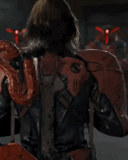 a man in a red suit is standing in front of robots