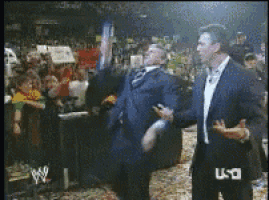 a man in a suit talks to another man in front of a crowd with usa written on the screen