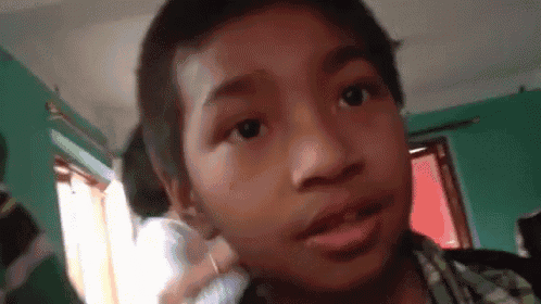 a young boy is talking on a cell phone in a room with green walls .