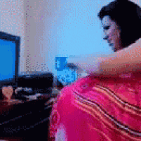 a woman in a pink dress is sitting in front of a computer monitor