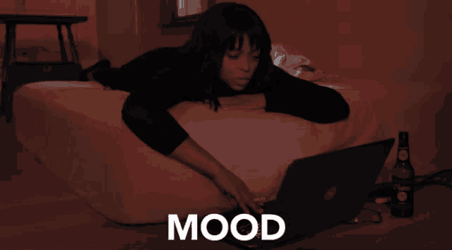 a woman is laying on a bed using a laptop and the word mood is on the bottom