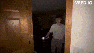 a man holding a flashlight in a dark room with the website veed.io on the bottom right
